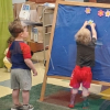 Two chidren place felt shapes on a blue easle in the library story room.