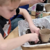 A young boy handles a planter.