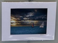 Two sailboats out at sea. A yellow sky peeks out behind dark clouds overhead.