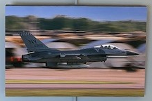 A fighter jet speeds feet above the ground mid takeoff. The jet is stable, but the background is blurred in rapid motion.