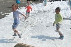 Children play in foam in the library parking lot