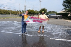 Mr Foamtastic and Mayor Anthony DellaPia hold a banner reading 'Best Summer Ever' in the library parking lot