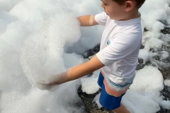 A boy lifts some foam into his hands