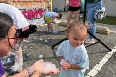 Youth Services Librarian Sara Figueroa presents some foam to a young child