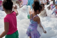 Children play in foam in the library parking lot