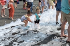 Children play in foam in the library parking lot