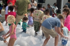 Children play in foam in the library parking lot