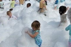 Children play in foam in the library parking lot